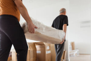Elderly man concentrating onto furniture he is carrying with younger coworker