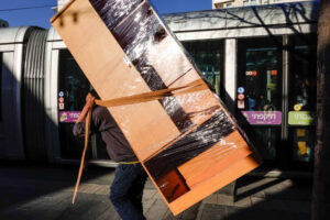 Jerusalem, Israel Jan 25, 2020 A man on Jaffa street carries a large load next to a tram.